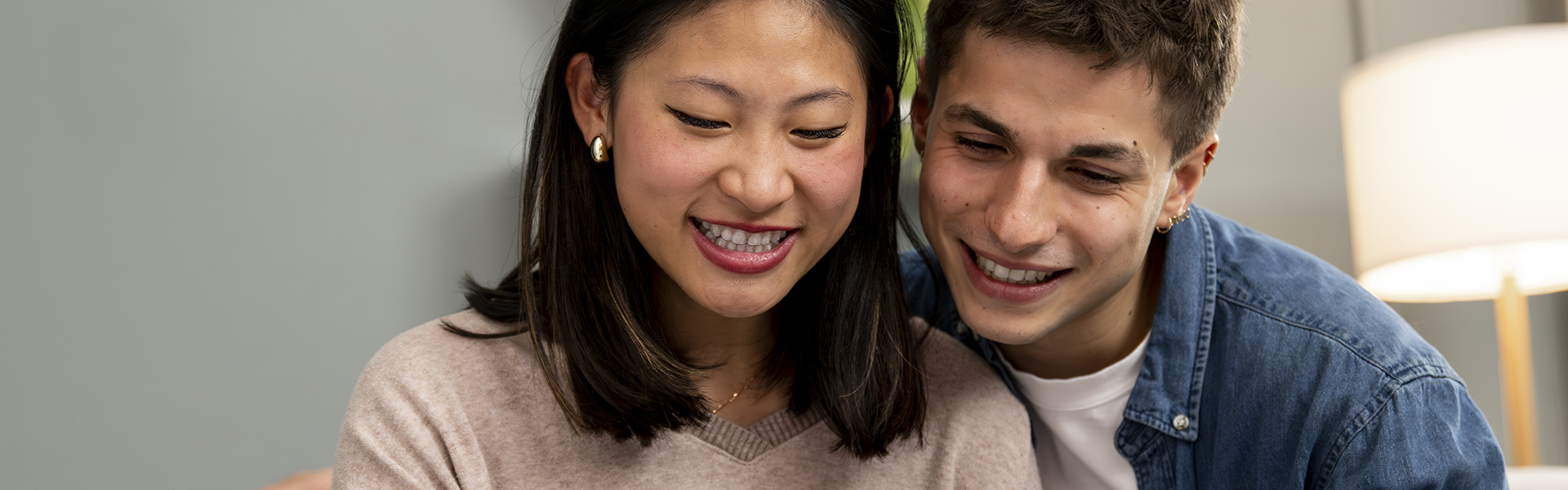 Young couple sit smiling at their laptop