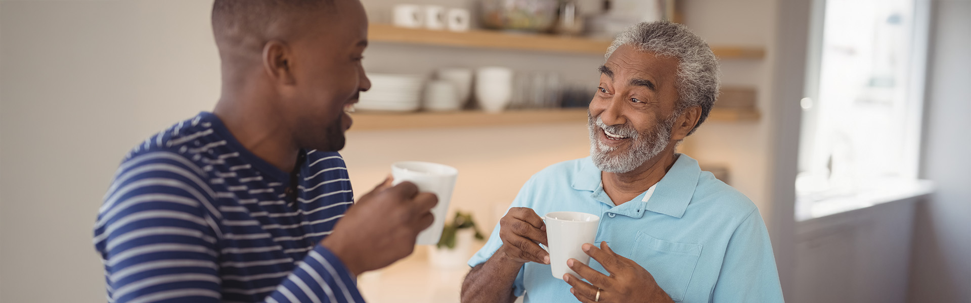 Smiling father and son interacting while having cup of coffee