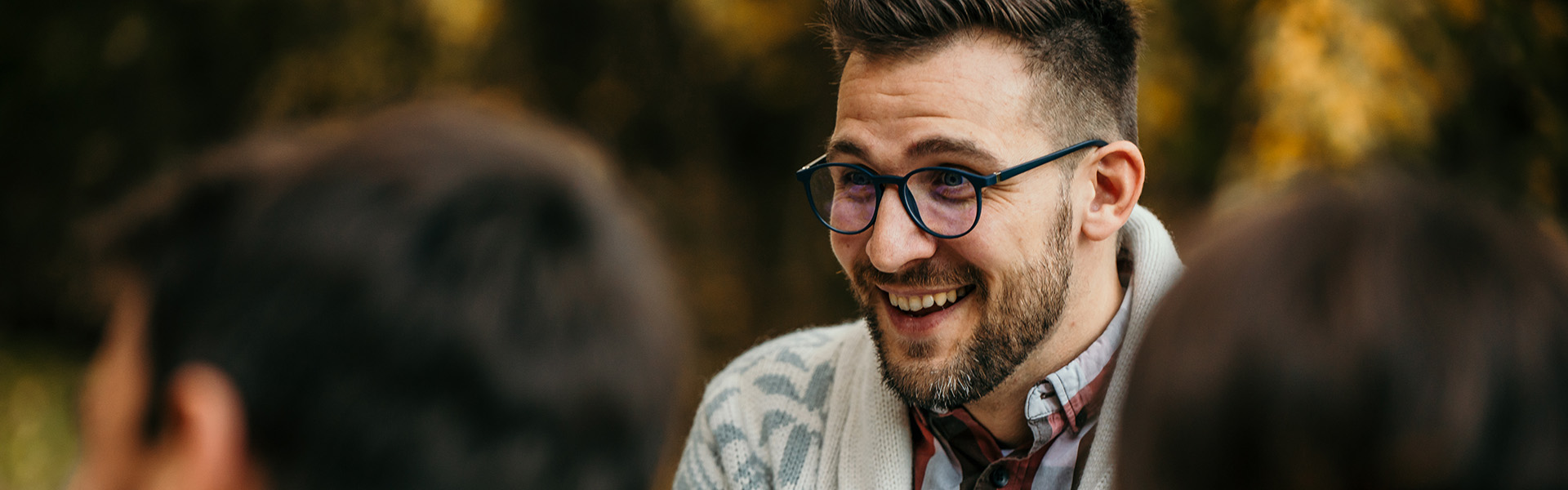 Smiling man talking to friends outdoors in autumn