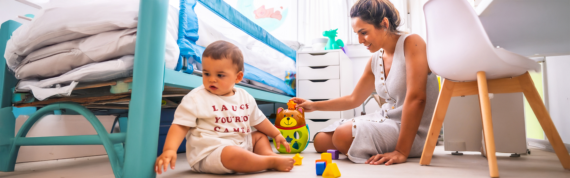 Young foster mother playing with child in the room with toys